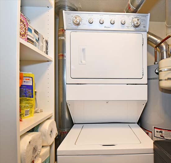Fully equipped laundry room with washer, dryer, ironing board, cleaning and laundry supplies.